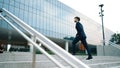 Skilled business man walking up stair while holding bag in the hand. Exultant. Royalty Free Stock Photo