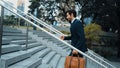 Skilled business man walking up stair while holding bag in the hand. Exultant. Royalty Free Stock Photo