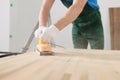 Skilled carpenter polishes wooden surface of office table