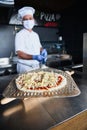 Chef  with protective coronavirus face mask preparing pizza Royalty Free Stock Photo