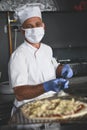 Chef  with protective coronavirus face mask preparing pizza Royalty Free Stock Photo