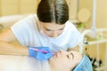 Skilled cosmetologist shaping lips with pencil for young girl before microblading.