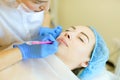 Skilled cosmetologist shaping lips with pencil for young woman before microblading.