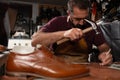 Cobbler at work repairing leather shoe with hammer and awl in a focused old-world workshop Royalty Free Stock Photo