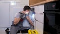 Skilled craftsman with flashlight examines pipes under sink Royalty Free Stock Photo