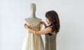 A skilled dressmaker taking precise measurements of a dress on a mannequin, exhibiting utmost care and detail