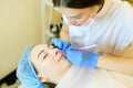 Skilled female cosmetologist shaping lips with pencil for young girl before microblading.