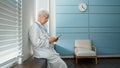 Skilled female doctor in white uniform consults patient at videocall sitting on windowsill in light hospital