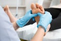 Skilled female masseur giving foot massage to young woman at beauty salon Royalty Free Stock Photo