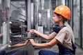 Skilled female repairing broken equipment in factory using wrench, in workwear