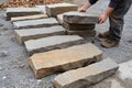Skilled hands arranging natural stone slabs for a rustic pathway installation Royalty Free Stock Photo