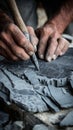 Skilled hands carving slate with chisel on rustic surface Royalty Free Stock Photo