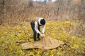 Skilled hiker man preparing army green raincoat tent to wearing it at outdoors on overcast rainy day.