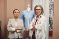 Skilled inspired confident team of two women tailors posing with a mannequin dummy wearing a blue shirt from new collection in a