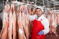 Butcher inspecting hanging raw lamb carcasses in cold warehouse