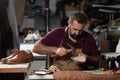 Leather craftsman forging shoes in a busy workshop with hammer, awl, and leather Royalty Free Stock Photo