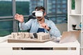 Skilled male architect reviewing an architectural project with augmented reality glasses in design office.