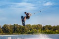 Skilled male wakeboarder jumping with backside rotation over water holding rope in hand Royalty Free Stock Photo