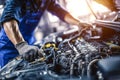 Skilled mechanic performing maintenance on a car engine in a workshop Royalty Free Stock Photo