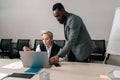 Skilled middle-aged 50s Caucasian female CEO executive manager wearing suit mentoring young african american male intern Royalty Free Stock Photo