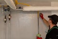 A qualified plumber diligently measuring pipes in a busy industrial setting during work hours Royalty Free Stock Photo