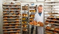 Baker arranging trays with bakery products on trolley Royalty Free Stock Photo