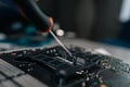 Skilled technician carefully removing aged thermal paste from computer motherboard CPU socket, readying precise surface Royalty Free Stock Photo