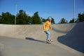 Skilled teenager boy wearing casual clothing and in roller blades riding on ramp