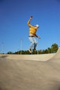 Skilled teenager boy wearing casual clothing and in roller blades riding on ramp