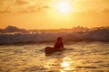 Skilled teenager riding surfboard and balancing along wavy sea at vibrant dusk.