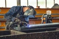 Skilled welder is seen at work in a large industrial factory, using a welding machine with sparks