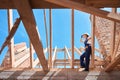 Skilled woman roofer adjusting hardhat standing on wooden frame of roof