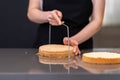 Skilled woman using string knife for separating cake layers in modern kitchen