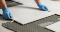 Skilled worker installing large white ceramic tiles during renovation project. Royalty Free Stock Photo