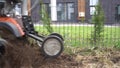 Skilled worker loosens soil with manual tractor in private house yard. Gimbal