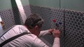 Skilled worker man make marks on tile to enlarge holes around water pipes