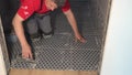 Skilled worker putting fugue on floor tiles in bathroom. Grouting ceramic tiles