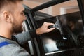 Skilled worker washing car window before tinting