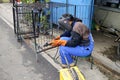 A skilled worker weld iron bars together to form a dog cage