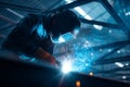 A skilled worker is welding a metal structure in a workshop. Bright sparks fly as they focus on the task, illuminated by the dim Royalty Free Stock Photo
