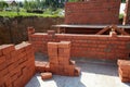 Skilled workers are constructing a brick wall with red bricks at a construction site. Royalty Free Stock Photo