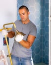Skilled workman wearing ordinary clothes repairing shower head in bathroom Royalty Free Stock Photo