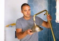 Skilled workman wearing ordinary clothes repairing shower head in bathroom