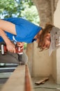 Skilled young female worker is using power screwdriver drilling during construction wooden bench gender equality Royalty Free Stock Photo