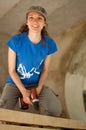 Skilled young female worker is using power screwdriver drilling during construction wooden bench gender equality Royalty Free Stock Photo