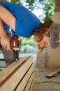 Skilled young female worker is using power screwdriver drilling during construction wooden bench gender equality Royalty Free Stock Photo