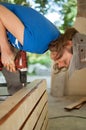 Skilled young female worker is using power screwdriver drilling during construction wooden bench gender equality Royalty Free Stock Photo