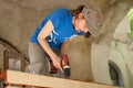 Skilled young female worker is using power screwdriver drilling during construction wooden bench gender equality Royalty Free Stock Photo