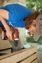 Skilled young female worker is using power screwdriver drilling during construction wooden bench gender equality Royalty Free Stock Photo