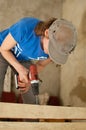 Skilled young female worker is using power screwdriver drilling during construction wooden bench gender equality Royalty Free Stock Photo